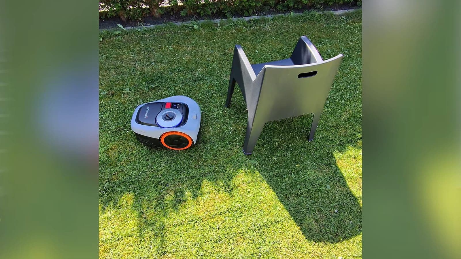 Navimow robotmaaier die nauwkeurig langs de poten van een tuinstoel manoeuvreert