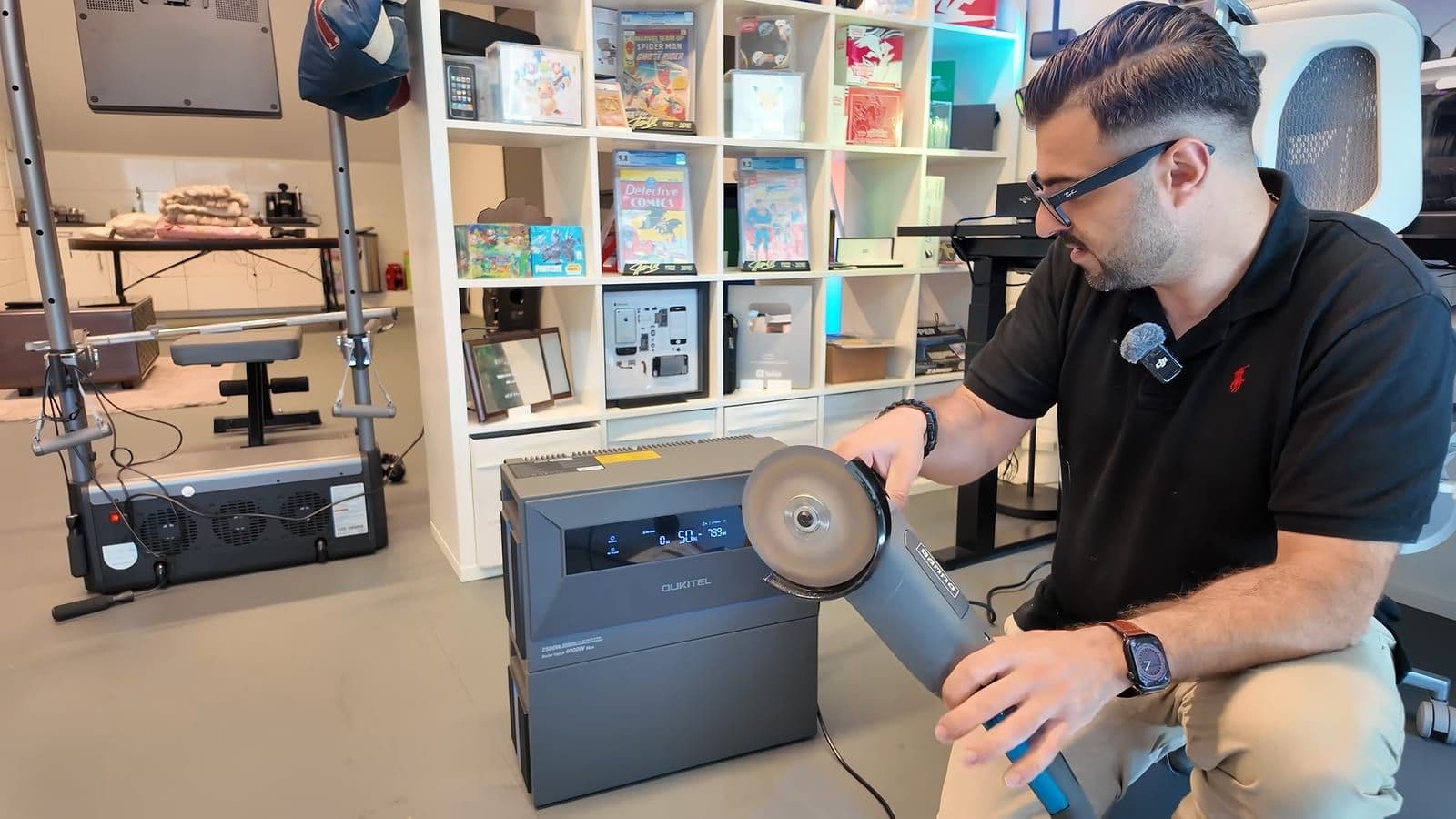 Zino houdt een haakse slijper vast naast de Oukitel EP2500 in een studio met een boekenkast vol comics